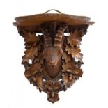 A SWISS CARVED LIMEWOOD WALL BRACKET WITH SERPENTINE SHELF SUPPORTED BY THE HEAD OF A MOUNTAIN