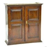 AN 18TH CENTURY STYLE OAK MURAL CUPBOARD, ENCLOSED BY A PAIR OF DOORS WITH RAISED AND FIELDED