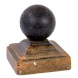 AN ENGLISH CIVIL WAR IRON CANNONBALL, ON OAK BASE, 17CM H