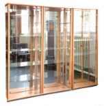 A SET OF THREE CONTEMPORARY LIGHT LAMINATE DISPLAY CABINETS WITH GLASS FULL LENGTH DOORS, 66CM W