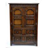 A 17TH CENTURY STYLE OAK CUPBOARD WITH PANELLED DOORS BENEATH NULLED FRIEZE AND FITTED WITH TWO