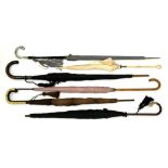 A BUNDLE OF VINTAGE WALKING STICKS AND UMBRELLAS, INCLUDING A GERMAN SILVER HANDLED EXAMPLE, EARLY