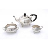 AN ART NOUVEAU SILVER THREE PIECE HAMMER TEXTURED TEA SERVICE with whiplash handles, teapot 11.5cm