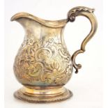 A SILVER CREAM JUG, CONVERTED FROM A MUG AND CHASED WITH FLOWERS AND FOLIAGE AT LATER DATE, 11CM