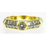 A DIAMOND RING THE LARGER HEXAGONAL COLLET FLANKED BY DIAMOND SET SLOPING SHOULDERS IN GOLD MARKED