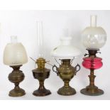 A BRASS OIL LAMP WITH CRANBERRY GLASS FOUNT AND GLASS SHADE 55CM H AND THREE OTHER BRASS OIL LAMPS