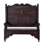 A VICTORIAN 'ANTIQUARIAN TASTE' CARVED AND STAINED OAK SETTLE, C1870 with bold mask terminals, 134cm