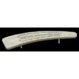 A VICTORIAN IVORY CRIBBAGE BOARD CARVED FROM A SECTION OF TUSK, 34CM L