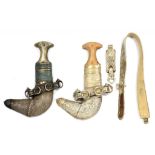 TWO OMANI HORN HILTED AND SILVER DECORATED DAGGERS, JAMBIYAS, AND SHEATHS AND A SIMILAR BELT, 20TH