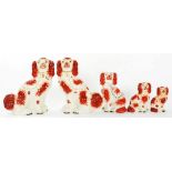 THREE AND A PAIR OF SIMILAR STAFFORDSHIRE EARTHENWARE MODELS OF SPANIELS WITH IRON RED SPONGED