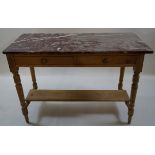 A Victorian pine wash stand with marble top, two frieze drawers and turned legs linked by a shelf,