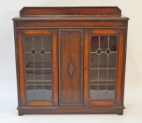 A mid 20th century oak display cabinet with two stained glass and lead doors on plinth base with