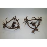 A pair of chandeliers, each formed out of three stags antlers,