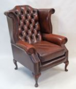 A late 20th century leather button back, wing arm chair with cabriole legs,