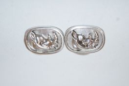 A pair of silver coloured cufflinks, with a design of a rhinoceros,