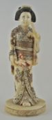 An early 20th Japanese carved ivory figure of a lady wearing a kimono holding a flowering branch,