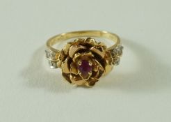 A 14 carat gold flower head ruby and diamond ring, the rose type flower centred with a ruby,
