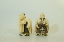 Two early 20th century stained ivory netsuke, each of a figure holding a fruit, 5.6cm high and 5.