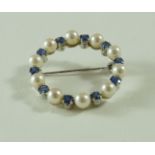 A cultured pearl and sapphire circlet brooch, stamped '750', 3.