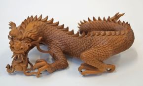 A carved hardwood figure of a dragon chasing a flaming pearl,