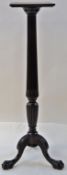 A mahogany torchere with carved and reeded column support on three shaped legs and carved paw feet,