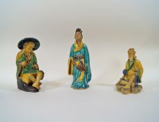 Three Chinese mudman figures, of a figure seated wearing a hat, 12.