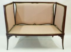 An Edwardian mahogany framed two seat sofa with raised back and arms on tapering splayed legs,