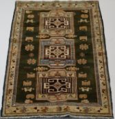 WITHDRAWN A Caucasian rug with three rectangular medallions on a green field within one wide border,