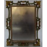 A wall mirror with decorative carved wood and painted frame,