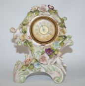 A late 19th century German porcelain clock, case of Rococo form, encrusted with flowers and figures,