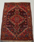 WITHDRAWN A Caucasian rug with central hooked medallion on a dark field with red spandrels within