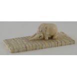 An early 20th century carved ivory figure of an elephant on a rectangular fossilized mammoth tusk