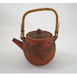 A Chinese red stoneware teapot, with bamboo handle and pierced liner, embossed with dragons, 17.