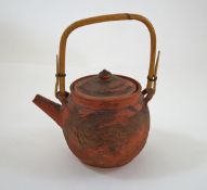A Chinese red stoneware teapot, with bamboo handle and pierced liner, embossed with dragons, 17.