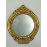 A round wall mirror in gilded frame with plaster scrolls, 31cm high,