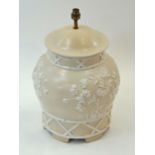 An Italian pottery lamp base moulded with flowers on a cream ground,