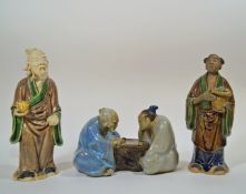 Three Chinese  mudman models, of two figures playing chess, 13cm wide, a wiseman holding a fruit,