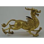 A Chinese gilded bronze figure of a dragon cast with horns, wings and legs out stretched,