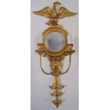 A gilt framed wall mirror with eagle crest and two candle sconces, 77cm high,