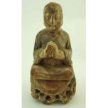A carved wooden figure of Buddha praying with legs crossed on a pierced base,