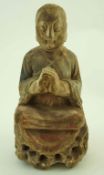 A carved wooden figure of Buddha praying with legs crossed on a pierced base,