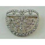 An Edwardian diamond brooch, of laurel leaf design enclosed within a semi circular frame,