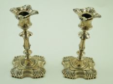 A pair of silver square candlesticks in late George II style, with acanthus chased corners,