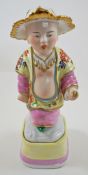 A German porcelain figure of a Chinaman, his leaf shaped hat picked out in gilt,