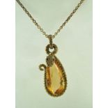 A pear shaped golden topaz in a gold serpent mount set with yellow diamonds to the body and ruby