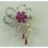 A white metal floral spray brooch, the six petal flower and centre set with round  mixed cut rubies,