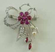 A white metal floral spray brooch, the six petal flower and centre set with round  mixed cut rubies,