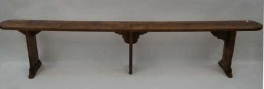 A French fruitwood bench, with three plank legs,