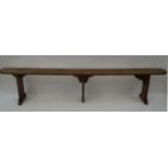 A French fruitwood bench, with three plank legs,