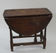 An oak drop leaf oval occasional table on turned legs linked by rectangular stretchers, 51cm high,